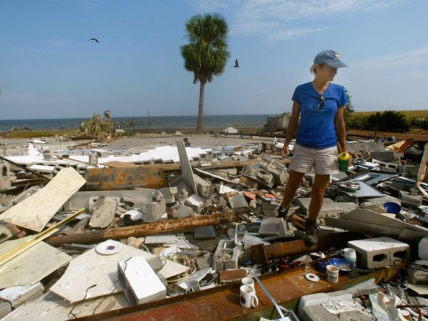 A woman viewing her house after a hurricane